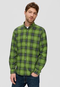 Green plaid button-up shirt featuring white and navy checks, long sleeves, and a collar, paired with blue jeans. Cotton material visible.