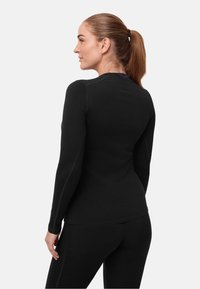 Parte superior atlética negra de manga larga hecha de tela elástica, con un diseño ajustado, costuras contrastantes y un cuello redondeado.