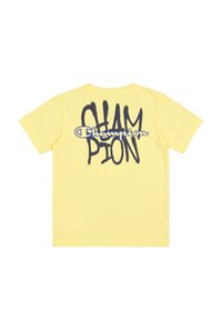 Camiseta amarilla de manga corta con la palabra "CHAMPION" impresa en texto negro de trazo de pincel y un contorno azul en la parte posterior. Fabricada con material de algodón suave.