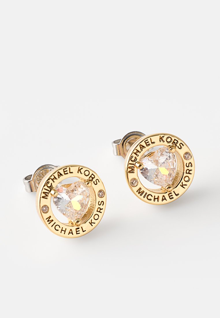 Pendientes de botón en tono dorado con una gema clara central, rodeada por un diseño circular con la inscripción "MICHAEL KORS".