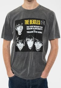 Gray cotton T-shirt featuring a graphic print of four Beatles faces with the text "THE BEATLES" and song titles in yellow and white.