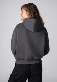 Grijze hoodie met een ontspannen pasvorm, geribbelde manchetten en tailleband. Zachte textuur, voorzien van een grote capuchon en een eenvoudig ontwerp.