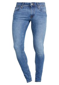 Jeans pitillo de mezclilla azul con un acabado desteñido, cinco bolsillos, cremallera frontal y corte estrecho en las piernas. La tela tiene una textura suave.