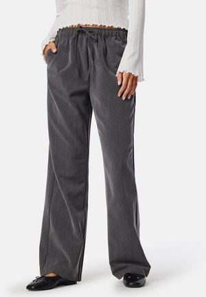 Grijze, wijde broek met een textuurafwerking, voorzien van een elastische tailleband en trekkoord, gestyling met een wit gebreid top.
