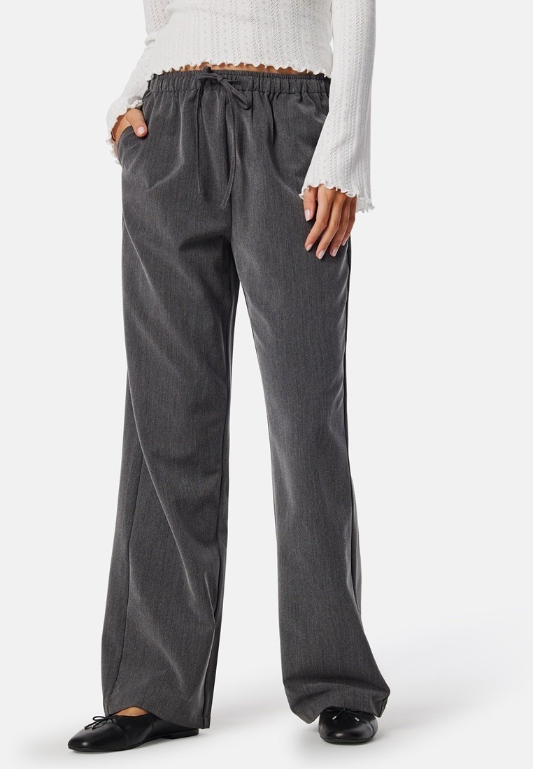 Grijze, wijde broek met een textuurafwerking, voorzien van een elastische tailleband en trekkoord, gestyling met een wit gebreid top.