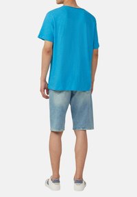 Hellblaues Kurzarm-T-Shirt aus weichem Stoff, kombiniert mit hellen Jeansshorts, die einen lockeren Schnitt und minimale Details aufweisen.