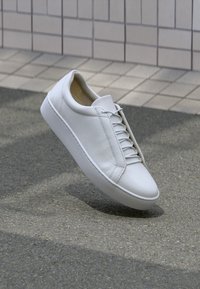 Weiße Ledersneaker mit klassischer runder Zehenpartie, minimalistischem Schnürdesign und glatter Textur sowie flacher Gummisohle.