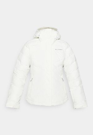 White insulated jacket with a high collar and adjustable hood. Features zippered side pockets and diagonal quilted pattern. Columbia branding visible.