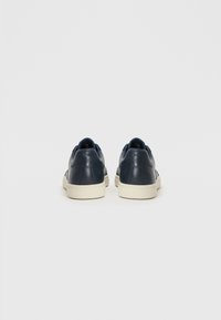 Navy leather sneakers with white rubber soles, Minimalist design featuring smooth texture and subtle stitching detail at the back.