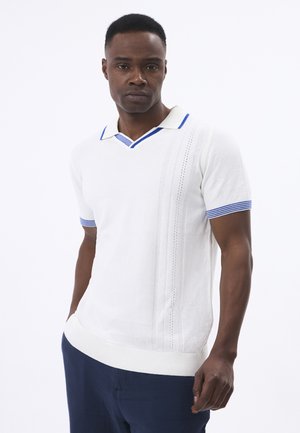 Polo shirt en tricot blanc avec des accents bleus sur le col et les poignets, présentant un détail rayé texturé sur le côté. Ourlet droit.