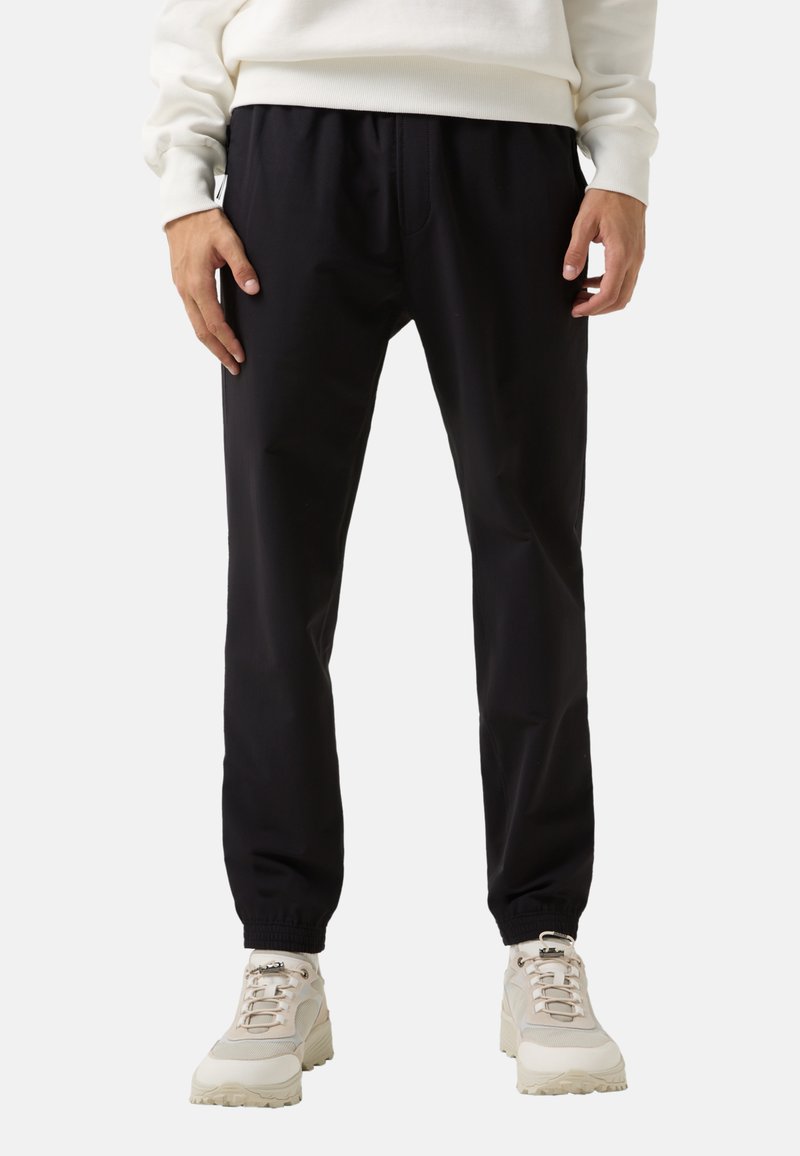 Sorte joggerbukser med elastisk talje, tætsiddende ben og sidelommer, lavet af glat, let materiale. Casual pasform.