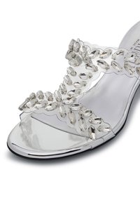 Sandal con tacco trasparente caratterizzata da una tomaia trasparente decorata con brillanti strass a forma ovale e una soletta metallica lucida.