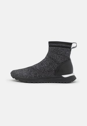 Schwarz-grauer gestrickter High-Top-Sneaker mit strukturierter Sohle und Zuglasche an der Ferse, von der Seite auf weißem Hintergrund gezeigt.