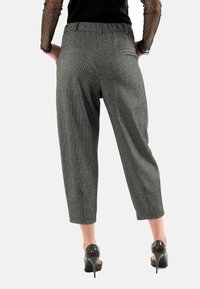 Grijze, gestructureerde, met een ruitpatroon versierde broek met een tapered ontwerp, voorzien van een achterzak en een elastische tailleband, gecombineerd met zwarte hakken.