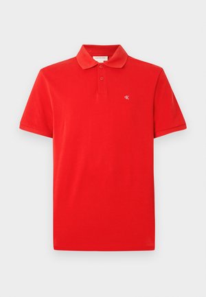 Polo rouge en coton, doté d'un col classique, de manches courtes, et d'un petit logo sur la poitrine. Texture lisse et coupe ajustée.