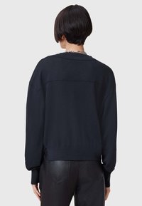 Felpa blu scuro con vestibilità comoda, polsini e orlo a coste. Tessuto morbido con un design semplice. Abbinata a pantaloni in pelle nera.
