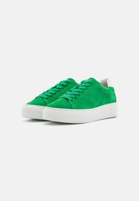 Green suede sneakers with white rubber sole, featuring flat laces, rounded toe, and contrasting stitching. Minimalist design with soft texture.