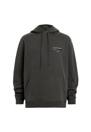 Donkergrijze hoodie met een kangoeroezak, koordjes en een kleine logo patch in zwart-wit op de borst. Zacht materiaal en een ruime pasvorm.