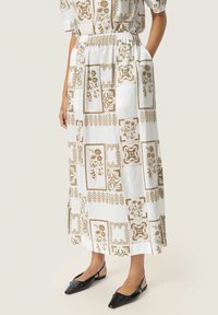 Hvid midi nederdel med brune blomster- og geometriske mønstre, elastisk talje, sidelommer og flade sorte slingback sko.