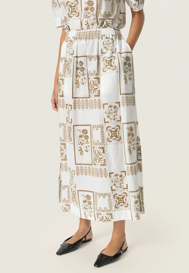 Hvid midi nederdel med brune blomster- og geometriske mønstre, elastisk talje, sidelommer og flade sorte slingback sko.