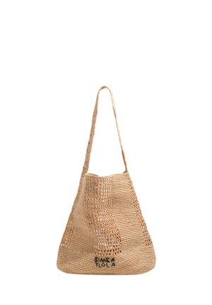 Beżowa, pleciona słomiana torba typu tote z długim paskiem i czarnym, haftowanym napisem „BINX A TOLA” blisko dolnej krawędzi.