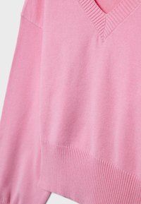 Ružový sveter s výstrihom do V z mäkkej látky, s rebrovanými manžetami a lemom, hladkou textúrou a voľným strihom.