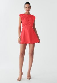 Abito rosso con corpetto aderente caratterizzato da una texture plissettata, maniche a giro e gonna svasata. Tessuto liscio e design alla lunghezza del ginocchio.