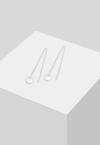 Orecchini in argento con catene allungate e dischi circolari all'estremità, caratterizzati da una texture liscia e un design minimalista.
