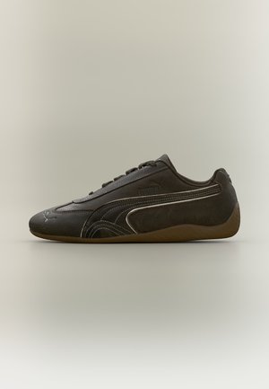 Ciemnobrązowy sneaker Puma z niskim profilem, bocznym paskiem, sznurowanym przodem oraz gumową podeszwą na neutralnym tle.