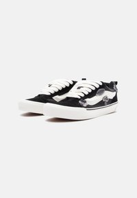 Black corduroy sneakers with white rubber soles and laces. Features embroidered gray and white floral accents on the sides.