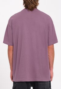 T-shirt en coton violet avec une coupe décontractée, des manches courtes et un col rond, offrant une texture lisse et sans motifs ni accents visibles.