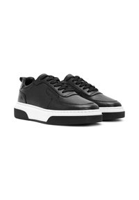 Zwarte leren sneakers met een gestructureerde afwerking, voorzien van platte veters, een gewatteerde witte tussenzool en een zwarte rubberen buitenzool.