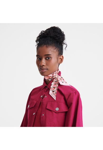 Fuchsia denim shirt with silver buttons and two front pockets, paired with a pink patterned scarf tied around the neck.