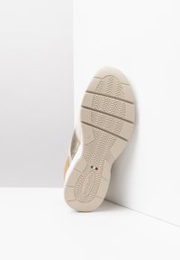 Sneaker con una suola in gomma beige testurizzata, parte superiore in oro metallico e accenti color taupe. Presenta un design slip-on e una soletta imbottita.