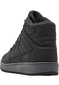Baskets montantes noires en cuir, avec une surface texturée, une cheville rembourrée et des accents à pois. Semelle en caoutchouc grise avec un motif de traction.