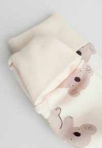 Lyserøde sokker med bjørnemønster, lavet af blødt stof med en glat tekstur. Bjørnen har en simpel illustration med subtile detaljer.