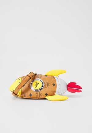 Brown synthetic handbag shaped like a fish, featuring yellow fins, silver accents, and a circular logo detail. Adjustable brown strap included.