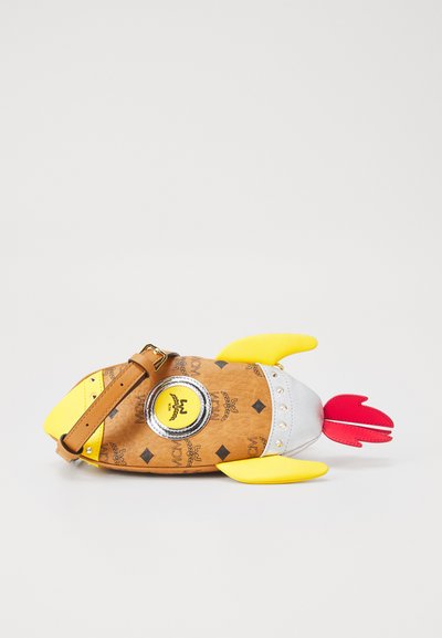 Sac à main synthétique marron en forme de poisson, avec des nageoires jaunes, des accents argentés et un détail de logo circulaire. Bandoulière marron réglable incluse.