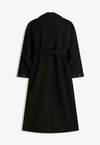 Lång svart kappa i texturerad tyg, med bälte, sidofickor och knäppta ärmslut. Bakdesign med klassisk krage.