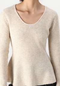 Beżowy sweter z prążkowanego dzianiny z szerokim okrągłym dekoltem, długimi rękawami i luźnym krojem, z fakturowaną powierzchnią i rozszerzanym dołem.