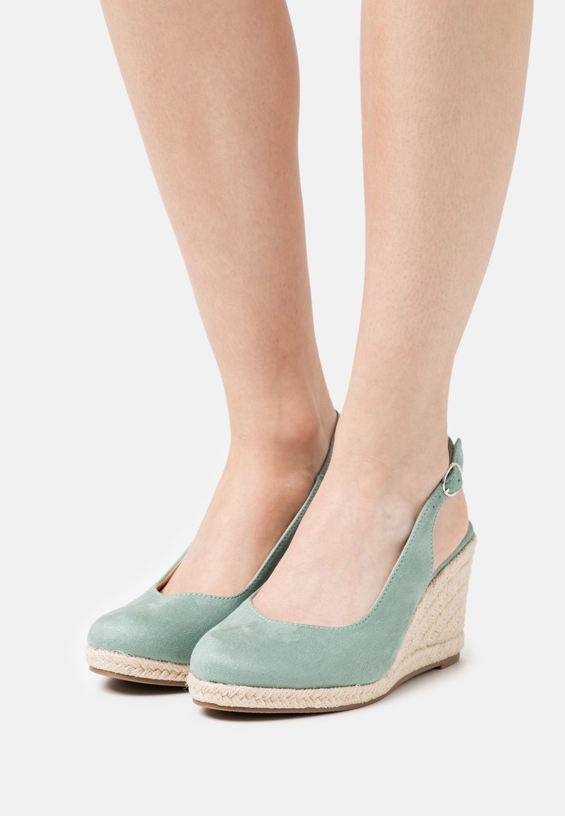 Zelené slingback klíny s semišovou texturou, s tkanou juteovou podrážkou a výřezy na bocích pro prodyšnost a styl.