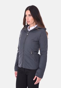 Giacca imbottita grigia con cappuccio, dotata di zip frontale, due tasche laterali, texture liscia e cordini regolabili in vita.