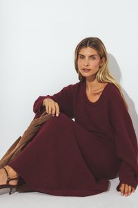 Burgundska pletena oblekica s dolgimi rokavi, širokim robom in okroglim izrezom, z mehkobo tkanine in sproščenim krojem.