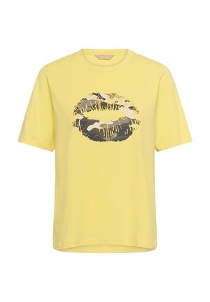Camiseta amarilla de manga corta con un gran gráfico de labios con estampado de camuflaje en negro, blanco y gris, con detalles de gotas de pintura amarilla en la parte delantera.