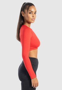 Langsleeve, cropped top in felrode stof. Soepele textuur met een aansluitend ontwerp, dat een slanke silhouet en ronde halslijn laat zien.