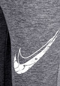 Witte versleten Nike swoosh logo gedrukt op gestructureerde grijze stof, waarschijnlijk onderdeel van sportkleding.