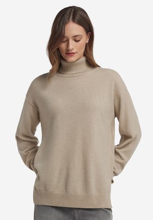 Beige polotröja i mjukt, texturerat tyg. Den har nedhasade axlar samt ribbade mudd och fåll, vilket ger en avslappnad passform.