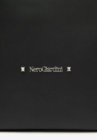 Sort struktureret lædertaske med et sølvlogo "NeroGiardini" og pyramide-accenter på begge sider.