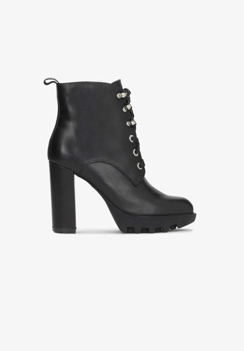 Bottine en cuir noir avec talon haut épais, fermeture à lacets avec œillets métalliques et semelle crantée pour une meilleure adhérence.