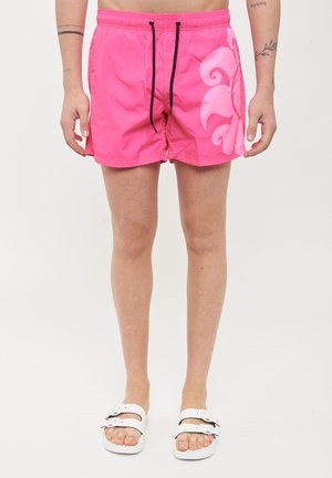 Pantaloni da bagno rosa con vita elasticizzata e cordino nero. Presentano un grande motivo a spirale bianco sul lato sinistro. Cuciture piatte; materiale leggero.